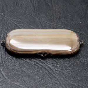 May include: A small, rectangular, cream-colored agate box with silver hinges and a smooth, polished surface.