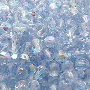 May include: A large quantity of light blue iridescent glass beads. The beads are faceted and have a teardrop shape.