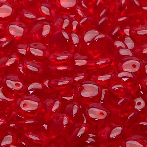 Peut inclure: Gros plan sur une grande quantité de petites perles de verre rouges. Les perles sont rondes et légèrement ovales. Elles sont translucides et ont une finition brillante.