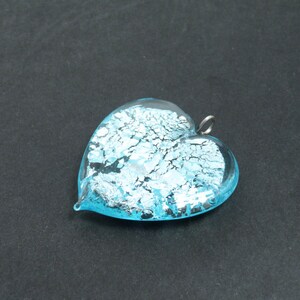 May include: A light blue glass heart pendant with silver flecks. The pendant has a silver loop for hanging.
