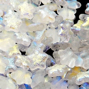 May include: A pile of iridescent white glass star-shaped beads. The beads have a slightly textured surface and are scattered randomly.