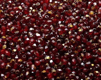 May include: A close-up image of a pile of small, faceted, red glass beads. The beads have a shiny, iridescent finish.