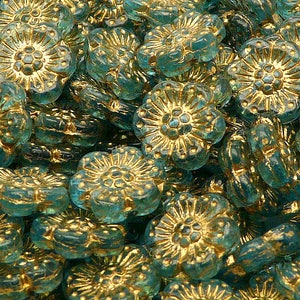 May include: A collection of teal-colored flower-shaped beads with gold-colored accents. The beads have a detailed floral design, with a raised center and petal detailing. These beads are suitable for jewelry making and craft projects.