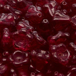 Könnte beinhalten: Nahaufnahme eines Haufens tief roter Glasperlen. Die Perlen sind in Form von kleinen Blüten mit mehreren Blütenblättern.