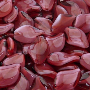 May include: A close-up of a pile of red glass beads shaped like petals. The beads are translucent and have a glossy finish.