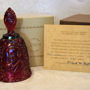 May include: A limited edition ruby red glass bell with a portrait of Thomas Fenton. The bell is part of the 1984 Connoisseur Collection and is numbered 4500 of 5000 pieces. The certificate reads "The Fenton Art Glass Company certifies this piece of glass as a totally handcrafted Limited Edition from the 1984 Connoisseur Collection. Each piece in this collection represents a special use of the glassmakers art. The treatment used in this piece is Ruby Satin Chicacent and it is number 4500 of an edition limited to 5000 pieces. Authenticated by Frank M. Fenton."