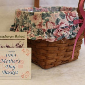 May include: A Longaberger Baskets 1993 Mother's Day Basket with a pink floral fabric liner and a pink ribbon.