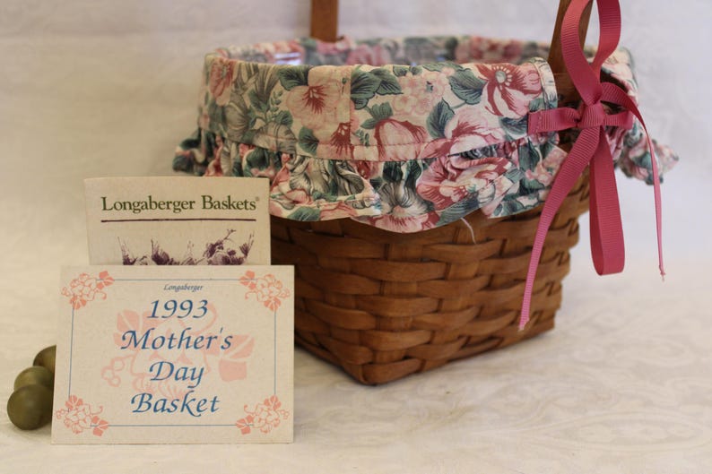 May include: A Longaberger Baskets 1993 Mother's Day Basket with a pink floral fabric liner and a pink ribbon.