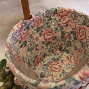 May include: A floral patterned fabric basket with wooden handles. The basket is empty and ready to be filled with items.