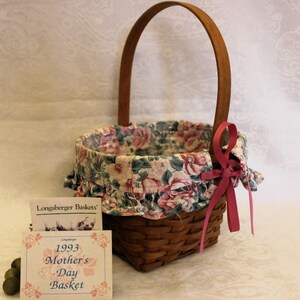 May include: A small wicker basket with a floral fabric lining and a pink ribbon. The basket is labeled "1993 Mother's Day Basket".