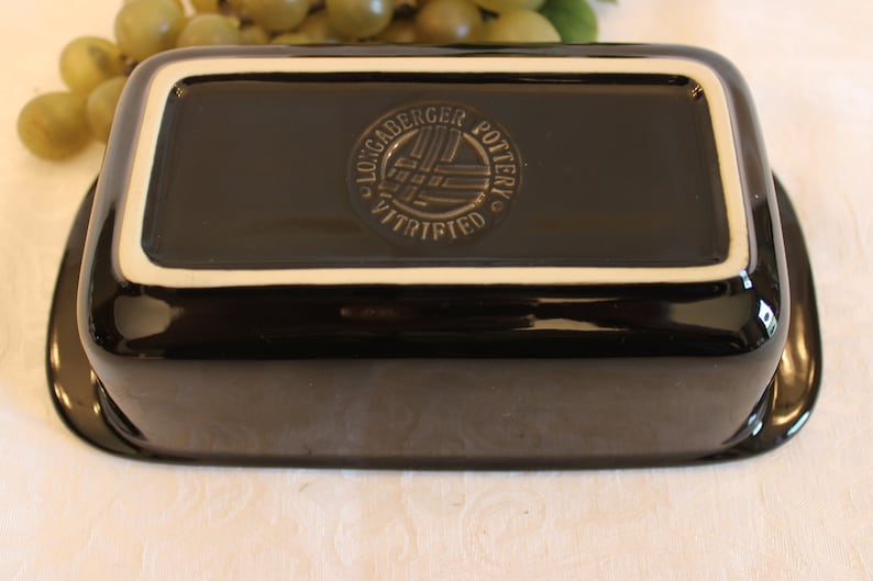 K&ouml;nnte beinhalten: Schwarze rechteckige Keramik-Backform mit wei&szlig;em Rand. Der Boden der Form tr&auml;gt ein kreisf&ouml;rmiges Logo mit der Aufschrift "Locgaderger Pottery Vitrified".