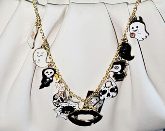May include: A gold chain necklace with various Halloween-themed charms, including ghosts, a cat, a spider, a skull, and a mouth. The charms are attached to a white handbag.