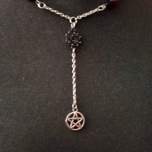 May include: A silver chain necklace with black beads and a silver pendant featuring a pentagram.