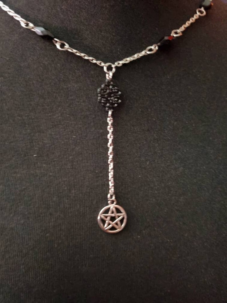 May include: A silver chain necklace with black beads and a silver pendant featuring a pentagram.