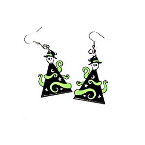 May include: A pair of black Halloween-themed earrings. Each earring features a witch hat design with a skull, stars, and green tentacles. The earrings have silver-colored fish hook ear wires.