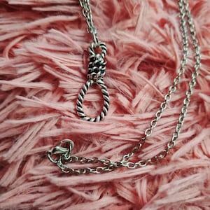 May include: A silver chain necklace with a twisted rope knot pendant.