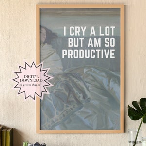 May include: A framed print with a light blue background and a woman's figure in the background. The text on the print reads "I cry a lot but am so productive."