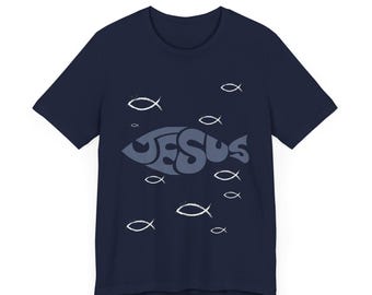 May include: A navy blue t-shirt with a graphic of a fish with the word "JESUS" inside. The fish is surrounded by smaller white fish.