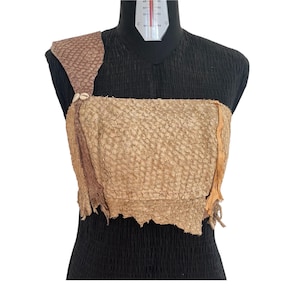 Op de afbeelding: Een bruin leren top met een textuur en rafelige randen. De top is versierd met een klein schelp accent.