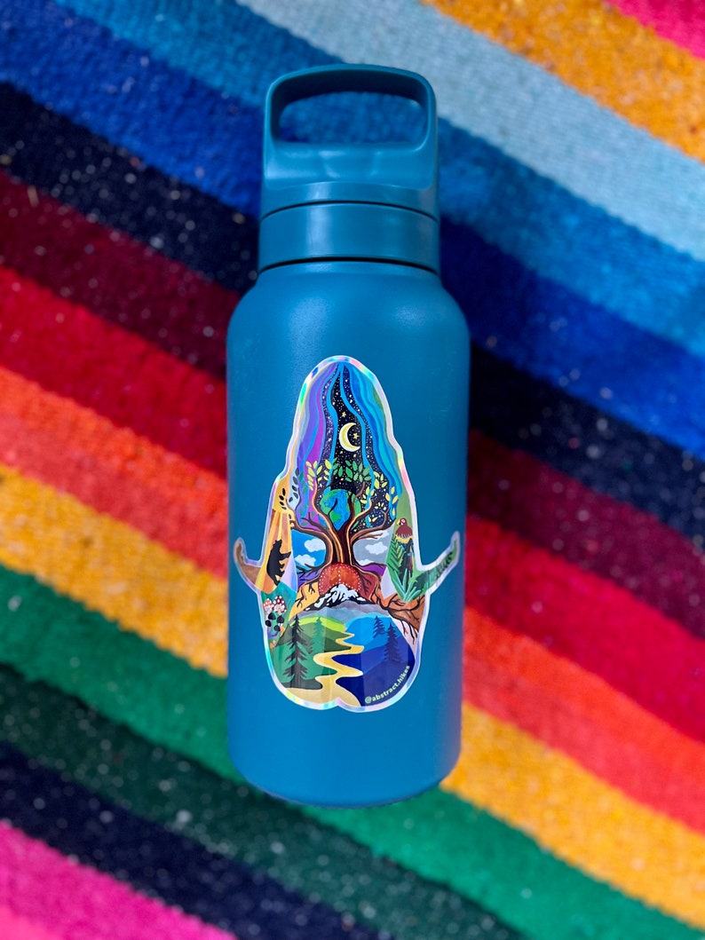 May include: A teal blue water bottle with a colorful sticker of a tree with a moon and stars in the background. The sticker has the text "Abstract Nature" at the bottom.