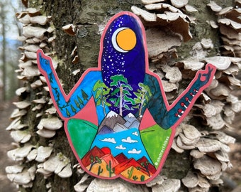 May include: A colorful sticker of a person in a yoga pose, with different landscapes and scenes layered on top of each other. The sticker features a night sky with stars and a crescent moon, a forest, mountains, a lake, and a desert scene. The sticker has the text "abstract.hikes" at the bottom.