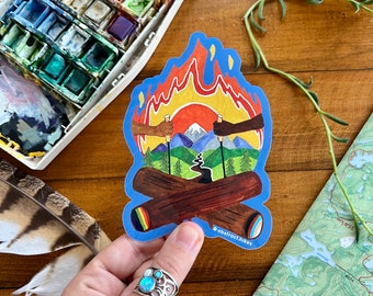 May include: A colorful sticker with a campfire scene. The fire is orange and yellow, and the flames are surrounded by blue. Two hands are reaching into the fire, holding sticks. There are mountains in the background, and the text "abstract hikes" is at the bottom of the sticker.