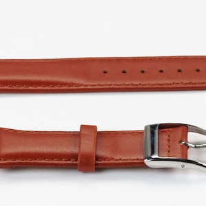 K&ouml;nnte beinhalten: Ein braunes Lederarmband mit einer silbernen Schlie&szlig;e. Das Armband hat einen gen&auml;hten Rand und mehrere L&ouml;cher zum Einstellen der Passform.