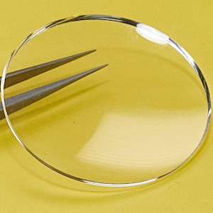 Puede incluir: Un cristal de reloj redondo y transparente con un borde ligeramente biselado.