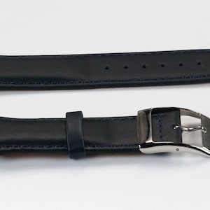 K&ouml;nnte beinhalten: Ein schwarzes Lederarmband mit blauen N&auml;hten und einer silbernen Schlie&szlig;e.