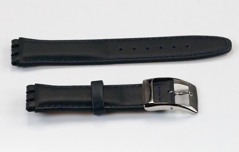 K&ouml;nnte beinhalten: Ein schwarzes Lederarmband mit blauen N&auml;hten und einer silbernen Schlie&szlig;e.