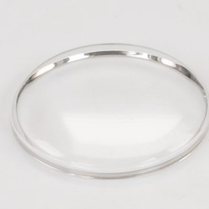 Op de afbeelding: Een helder glazen horlogeglas met een zilverkleurige rand.