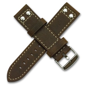 May include: Brown leather watch strap with white stitching and silver metal rivets. The strap has a buckle closure.