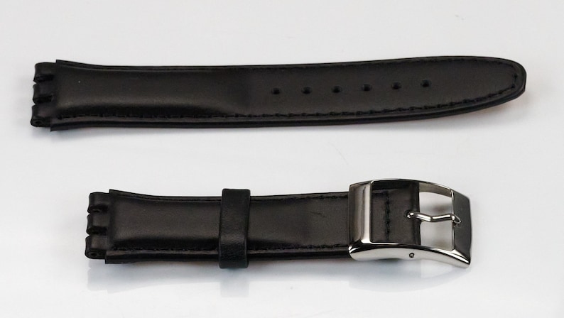 K&ouml;nnte beinhalten: Schwarzes Lederarmband mit silberner Schlie&szlig;e. Das Armband hat ein einzigartiges Design mit einer Reihe kleiner, rechteckiger Ausschnitte an den R&auml;ndern.