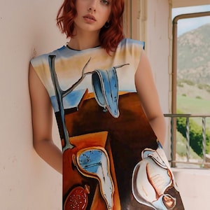Puede incluir: Vestido sin mangas con una pintura surrealista que presenta relojes derritiéndose, una rama de árbol y un fondo de paisaje. La obra de arte está en tonos de azul, marrón y blanco. El vestido tiene un cuello redondo y una silueta ajustada.