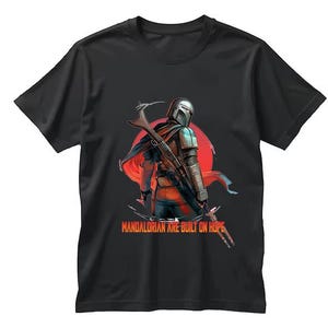 Op de afbeelding: Zwart t-shirt met een gedetailleerde illustratie van een Mandalorian krijger met een blastergeweer, tegen een rode zon. De tekst "Mandalorian are built on hope" staat eronder.