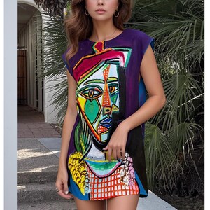 May include: A sleeveless mini dress featuring a vibrant, abstract cubist-style portrait print. The design incorporates bold blocks of purple, yellow, green, red, and blue, with a prominent face graphic centered on the front of the garment.