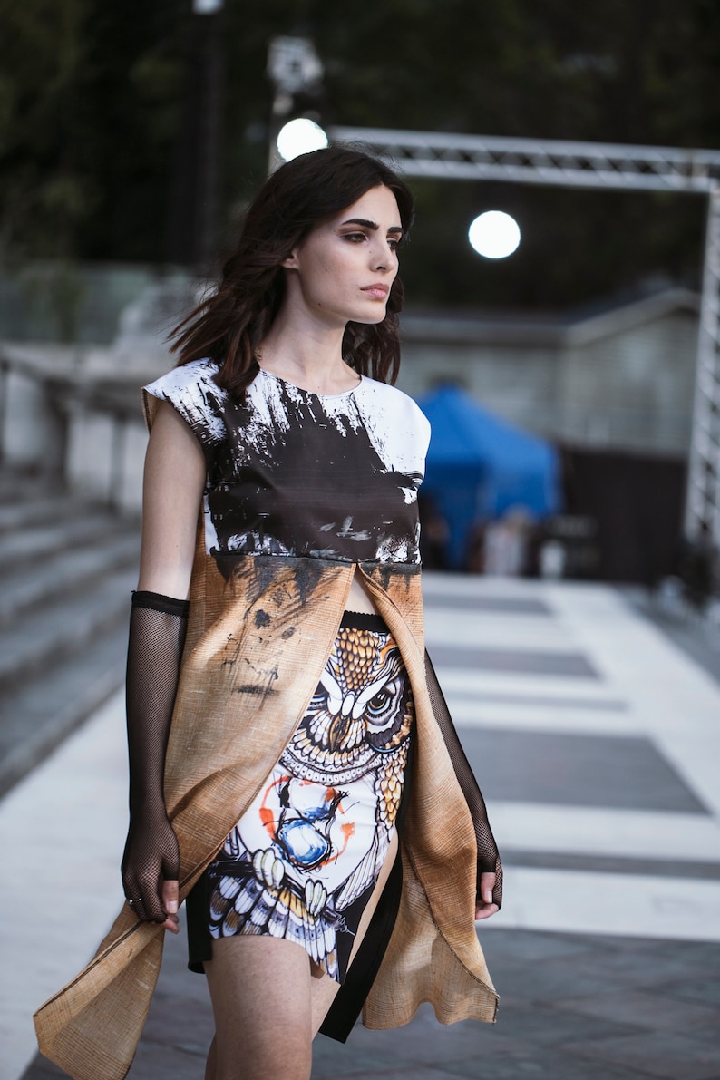 Peut inclure: Une femme portant un haut &agrave; imprim&eacute; abstrait noir et blanc avec une jupe &agrave; imprim&eacute; hibou marron et blanc. La jupe a une fente &agrave; l'avant et le haut est superpos&eacute; &agrave; la jupe.