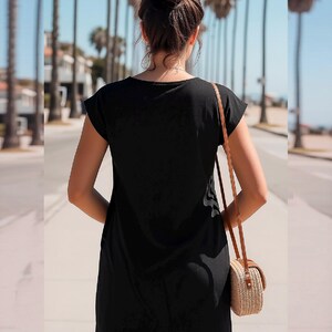 May include: A solid black short-sleeved dress with a simple round neckline and a straight hemline. The dress is worn with a small, round, woven straw crossbody bag featuring a thin brown leather strap that hangs over the shoulder.