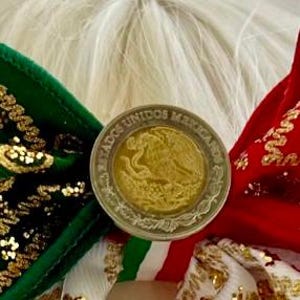 May include: A hair bow featuring green and red velvet fabric with gold glitter accents, centered with a Mexican coin displaying the text ESTADOS UNIDOS MEXICANOS and an eagle emblem. The bow includes white ribbon with gold floral patterns.