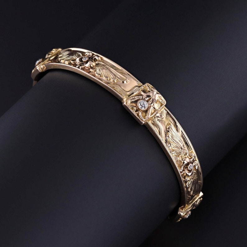 An alluring antique bangle depicting the Egyptian winged sun disk-- an ancient symbol of protection and divinity.  This 14k gold bangle dates to the early 1900s.  It is accented with birds and old European cut diamonds.