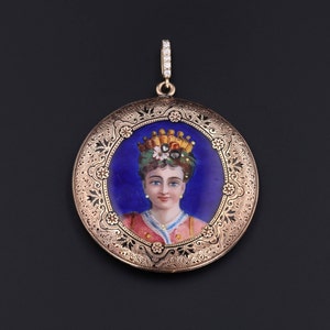 Pu&ograve; includere: Un ciondolo a medaglione in oro con un designo filigranato dettagliato. Il medaglione presenta un ritratto dipinto di una donna che indossa una corona e un abito rosa e oro. Lo sfondo del ritratto &egrave; di un blu profondo.