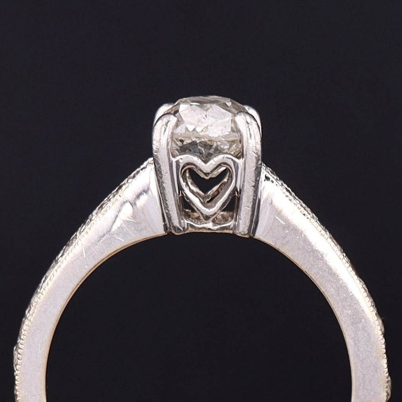 Puede incluir: Un anillo de compromiso de plata con un engaste en forma de coraz&oacute;n y un diamante redondo.