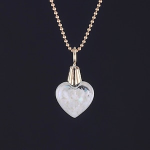 May include: A gold chain necklace with a heart-shaped glass pendant filled with white glitter.