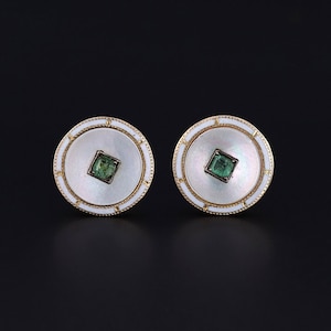 May include: A pair of round cufflinks with a white mother-of-pearl centre and a green gemstone set in a gold frame. The cufflinks have a gold rim with a white enamel border.