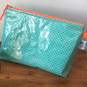 Large toiletry bag in coated cotton with geometric patterns in neon green, blue and orange colors with pockets inside