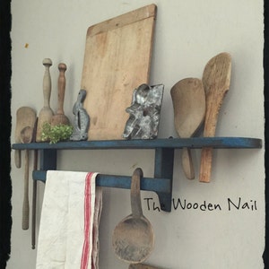 May include: A blue painted wooden shelf with a towel rack and hooks. The shelf is filled with vintage kitchen items, including wooden spoons, a rolling pin, a cutting board, and a metal cookie cutter. The text "The Wooden Nail" is visible in the lower right corner of the image.