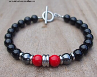 May include: Black and red beaded bracelet with a silver toggle clasp. The bracelet features black onyx beads, red coral beads, and silver spacer beads.