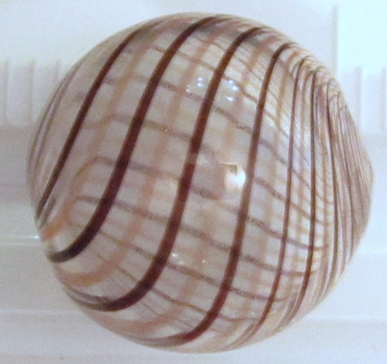 May include: A round, translucent object with a striped pattern. The stripes are dark brown and curve around the sphere, creating a grid-like effect. The object has a glossy finish and reflects light.