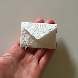 May include: A small white envelope made of textured paper.