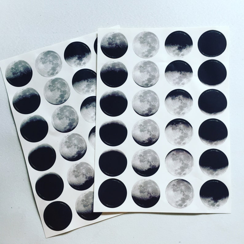 May include: A sheet of black and white moon phase stickers. The stickers are arranged in a grid pattern and feature different phases of the moon.